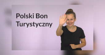 Grafika do filmu w polskim języku migowym. Po lewej stronie czarny napis: „Polski Bon Turystyczny”. Po prawej uśmiechnięta kobieta w średnim wieku macha w stronę kamery. Fioletowe tło.