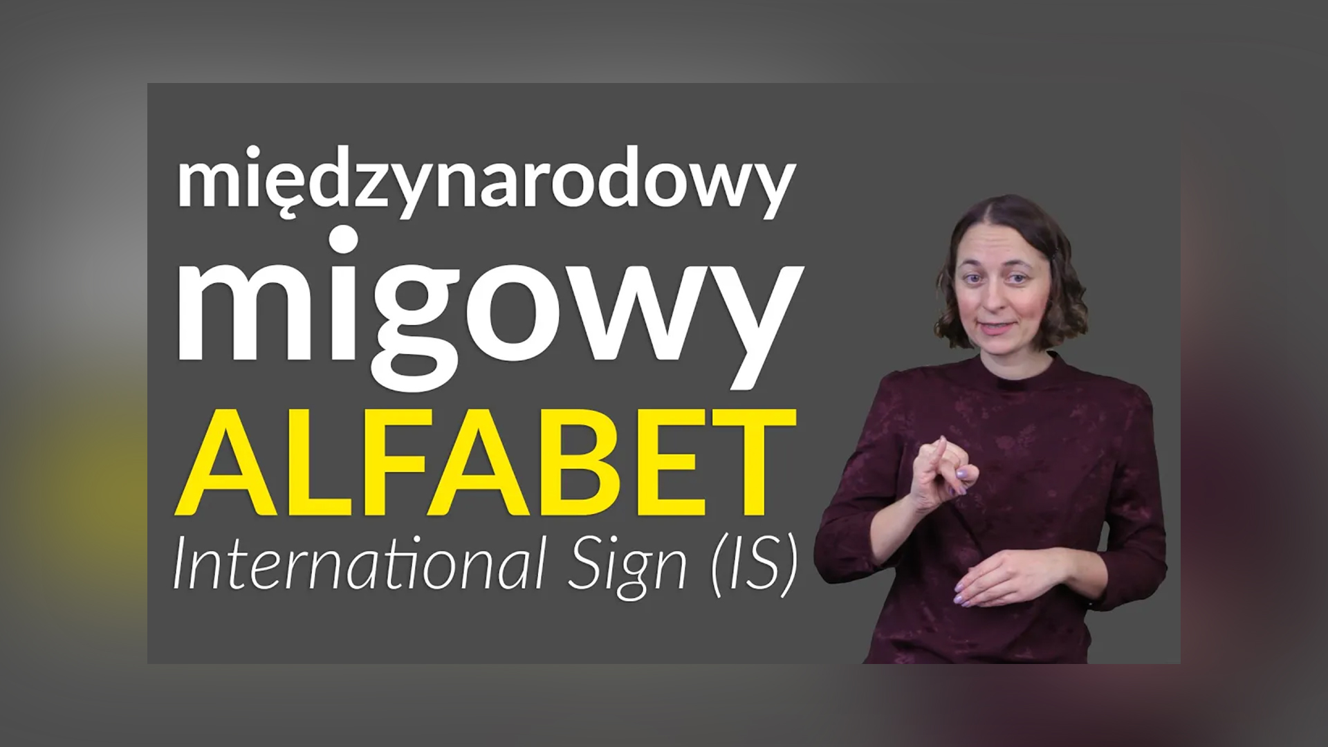 Grafika do filmu w PJM. Po prawej zdjęcie prowadzące Kingi Hołda-Justyckiej, po lewej napis: „Międzynarodowy migowy alfabet, International Sign (IS)”